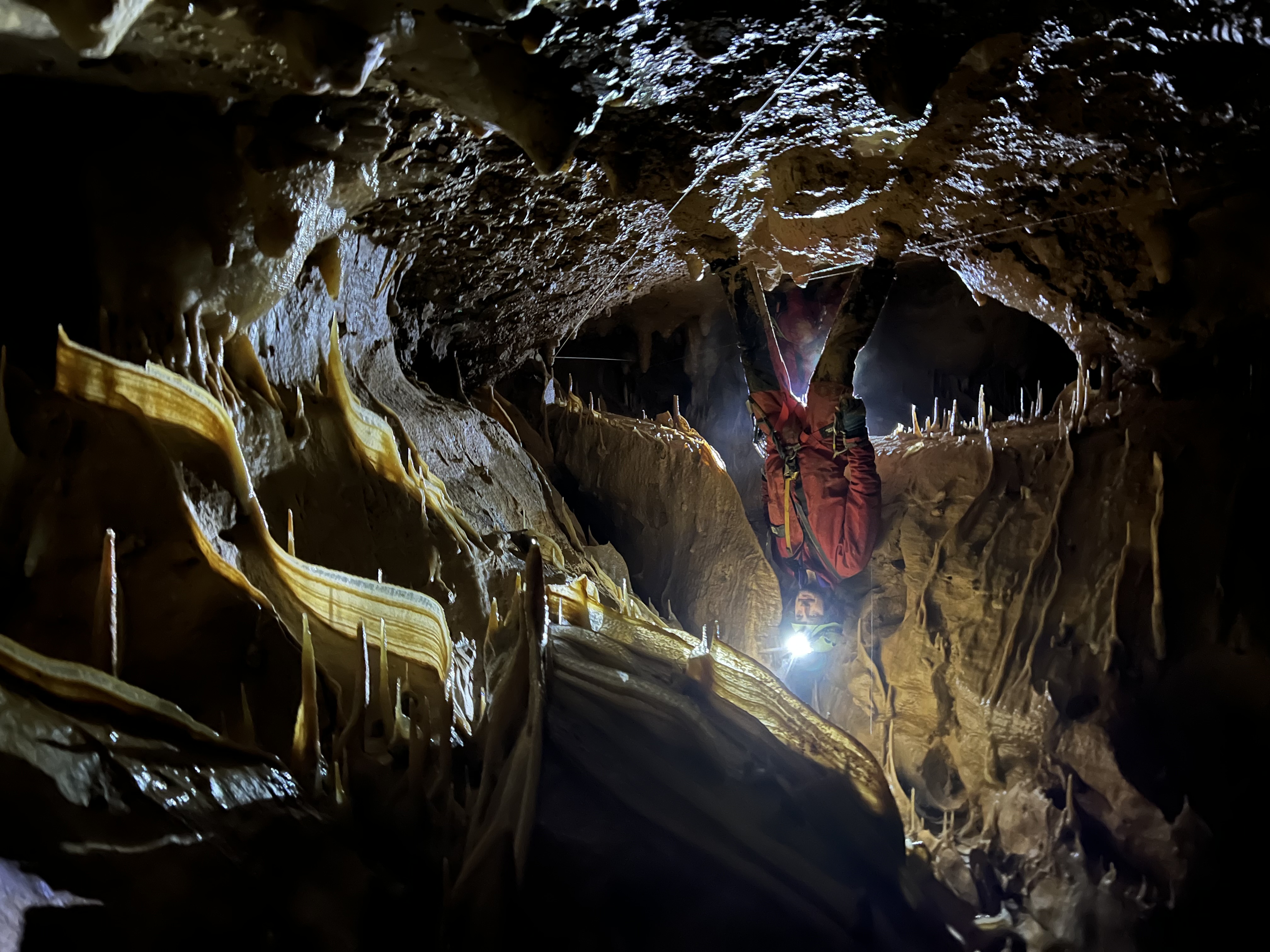 Initiation spéléologie - Spéléologue débutant dans une grotte avec des formations rocheuses et des stalactites, photo par Eva Lourau